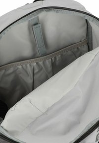 Lichtgrijze rugzakinterieur met een gepolsterd compartiment met een elastische bovenrand en een riem om een laptop of tablet te bevestigen.
