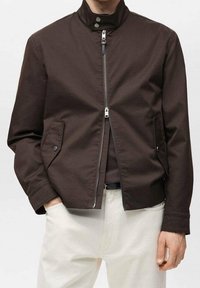 Braune Jacke mit Reißverschluss und Stehkragen, ausgestattet mit Seitentaschen und silbernen Metallakzenten. Hergestellt aus glattem, robustem Stoff.