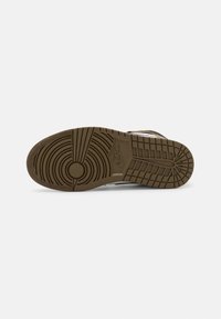 Nike shoe sole with circular and linear tread patterns. Color is brown with a textured surface. Features logo on the side.