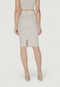 Falda lápiz beige con una abertura trasera, hecha de una tela lisa. Presenta un diseño ajustado y un cierre de cremallera oculta en la parte posterior.