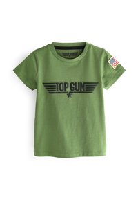 Zelené bavlněné tričko s krátkým rukávem, na kter�ém je černé logo "TOP GUN" a malá nášivka s americkou vlajkou na pravém rukávu.