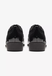 Schwarze Lacklederschuhe mit Brogue-Details, abgerundeter Spitze und gestapeltem Holzabsatz. Glatte Textur mit minimalen Akzenten.