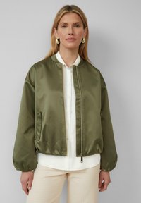 Veste bomber vert olive en satin, avec une fermeture éclair, des poches latérales et des poignets élastiqués pour un ajustement décontracté.