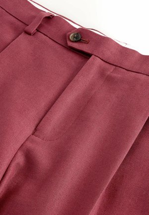 Sötétrózsaszín, testre szabott nadrágok elülső gombos záródással és látható övbújtatókkal, fehér háttéren.