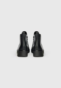 Schwarze Leder-Stiefeletten mit glatter Oberfläche, ausgestattet mit einem Seitenreißverschluss und einer dicken Plattformsohle für zusätzlichen Höhengewinn.