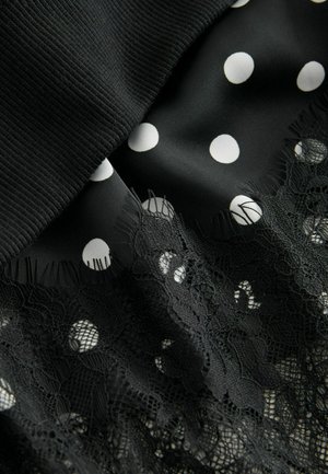Material negru cu buline albe suprapus peste dantelă. Prezintă un top texturat, cu striații, și detalii intricate de dantelă florală de-a lungul tivului.