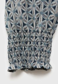 Polsino elasticizzato con bordo arricciato, realizzato in tessuto con fantasia nei toni del blu e del grigio, che presenta motivi floreali con accenti geometrici.