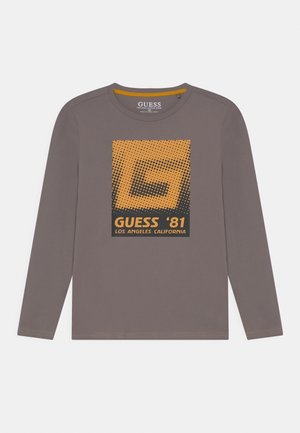 T-shirt gris à manches longues avec un graphisme orange et noir et le texte "GUESS '81 Los Angeles California" au centre devant.