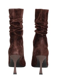 Stivaletti alla caviglia in suede marrone con un'asta morbida e pieghevole, tacco affusolato e texture liscia. Presentano un design elegante e minimalista.