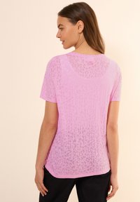 Camiseta de manga corta rosa con un patrón de leopardo transparente y escote redondo. Tejido suave y ligero con un dobladillo trasero ligeramente más largo.
