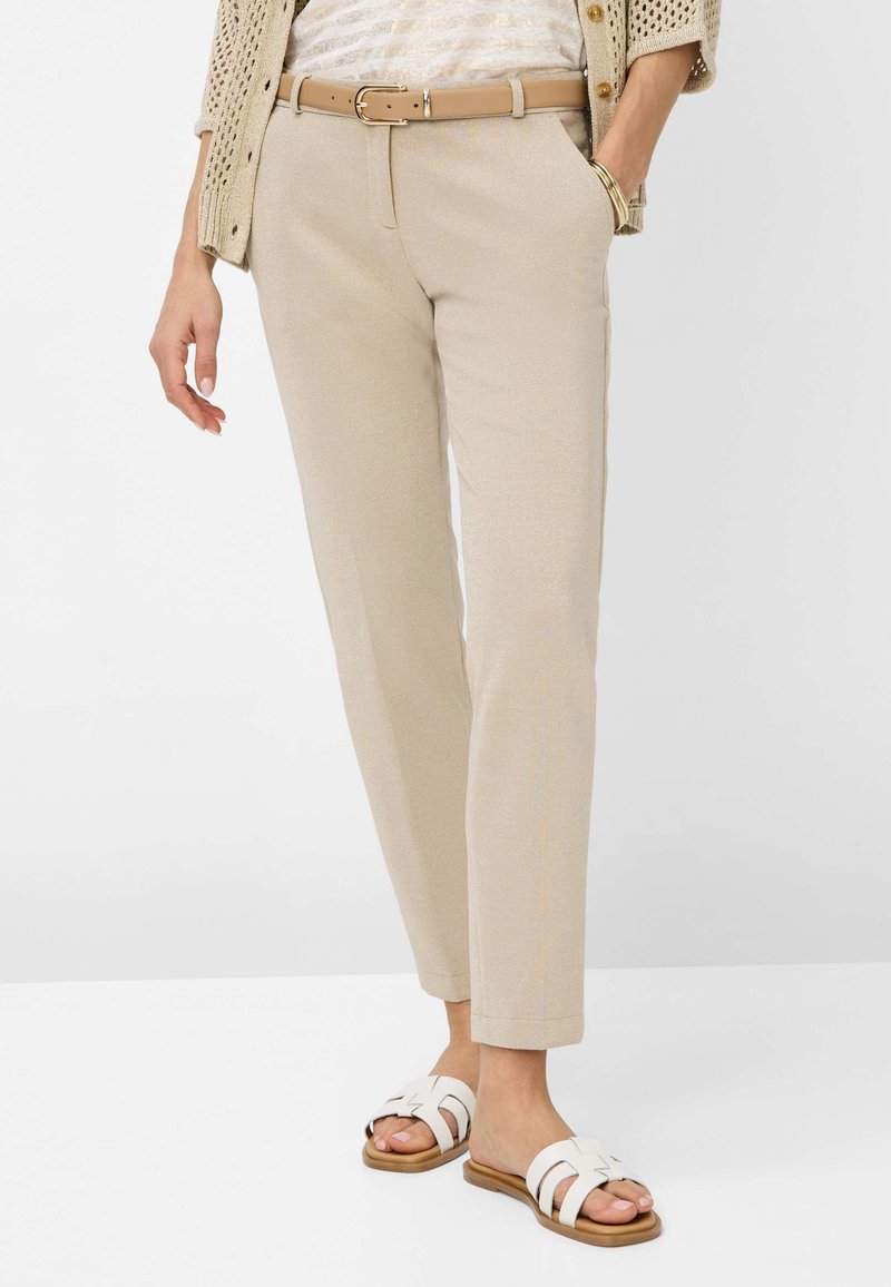 Beige maßgeschneiderte Hosen mit glatter Textur, geradem Schnitt und Gürtelschlaufen, kombiniert mit weißen Sandalen mit Riemchen-Design.