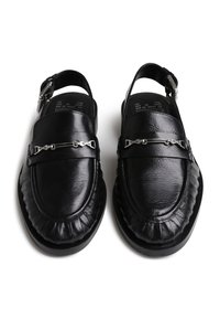 Zapatos de tacón en cuero negro con un acabado texturizado, que presentan un detalle plateado en la parte delantera y un diseño acolchado y fruncido en el borde.