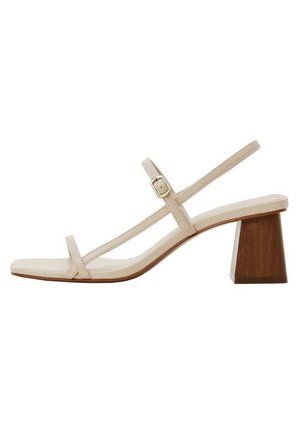 Sandale beige à lanières avec un orteil carré, des lanières fines et un talon en bloc en bois. Le matériau semble lisse avec un design minimaliste.