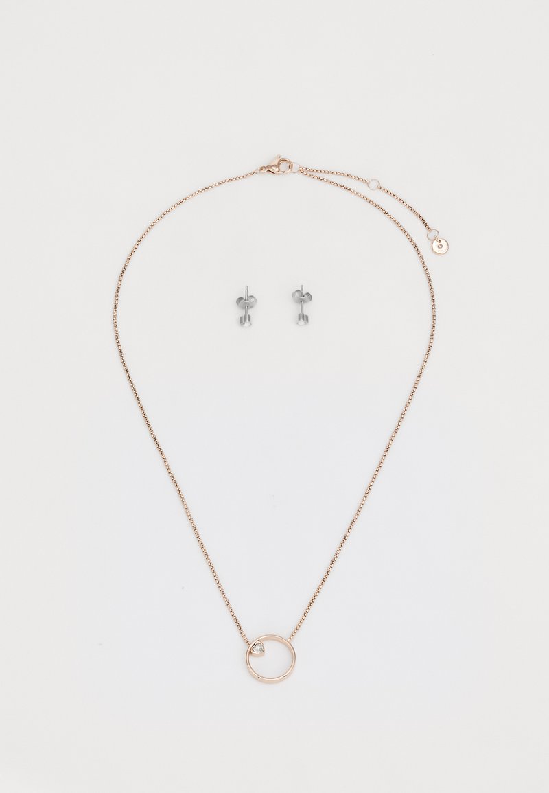 Collier chaîne en or rose avec un pendentif circulaire arborant une petite pierre précieuse transparente ; accompagné de boucles d'oreilles en argent avec des tops ronds.