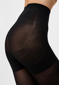 Leggings neri a vita alta con finitura traslucida, motivo testurizzato e dettagli sagomati sul retro per una silhouette modellata.