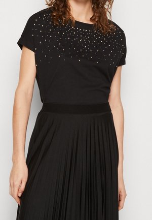 Sort kortærmet t-shirt med et glitrende design og metalstuds på den øvre front, parret med en plissert sort nederdel.