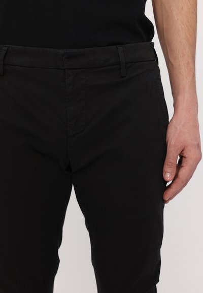 Svarta bomullsbuks med slim fit, med sidfickor och bälteslingor. Slät textur utan synliga mönster eller metalldetaljer.