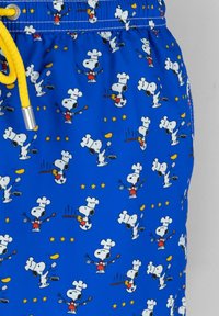 Pantaloni da bagno blu con un motivo a fumetti ripetuto di un cane chef, caratterizzati da un cordoncino giallo e illustrazioni di utensili da cucina e stelle.