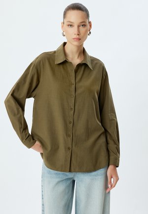 Camicia verde oliva con bottoni, colletto, maniche lunghe e vestibilità rilassata. Realizzata in un tessuto leggero e con una texture.