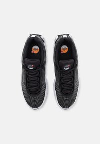 Svarta mesh-sneakers med en texturerad yta, som har en vit sula och svarta snören. Accentuerade med en cirkulär logotyp i orange och grått.