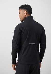 Zwarte sportjack met hoge kraag, gestructureerd patroon op de mouwen en reflecterende accenten op de achterkant voor zichtbaarheid.