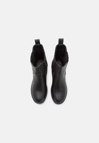 Botines de piel negra con textura suave, punta redonda, paneles elásticos en los laterales y lengüetas en la parte trasera para facilitar su puesta.