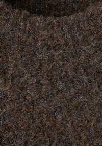 Tela marrón texturizada con un aspecto difuso, que presenta fibras rizadas de forma apretada y destellos de hilos azules y naranjas entrelazados.