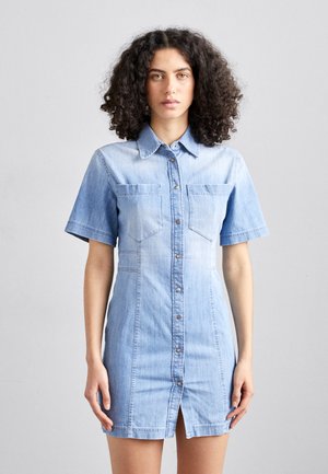 Vaaleansininen farkku-mekko, jossa on lyhyet hihat, napitus edessä, kaksi rintataskua ja halkio alaosassa. Mekko on muotoiltu istuvaksi.