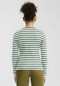 T-shirt à manches longues rayé avec une texture côtelée en teal et crème, au design ajusté et au col rond.