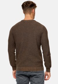 Brązowy sweter o teksturze z geometrycznym wzorem, z prążkowanymi mankietami i dolnym wykończeniem, dopasowany krój, pokazany z tyłu.