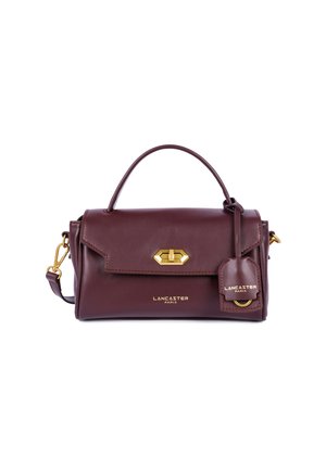 Borsa a mano in pelle bordeaux con manico superiore, accessori in tonalità oro, chiusura con pattina frontale e dettaglio etichetta per bagagli. Inclusa tracolla regolabile.