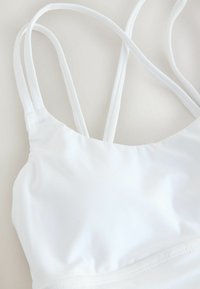 Witte bikini top met een soepel, rekbaar materiaal, dunne bandjes en een ronde halslijn met minimale naden.