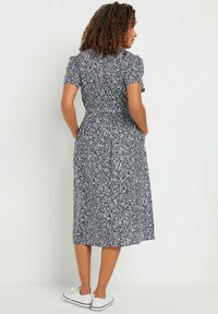 Abito midi blu navy con stampa floreale bianca, maniche a puff corte, vita aderente e gonna svasata; abbinato a sneakers bianche.