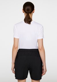 Vit kortärmad skjorta med rund halsringning, i kombination med svarta shorts som har resår i midjan och volangdetaljer på baksidan.