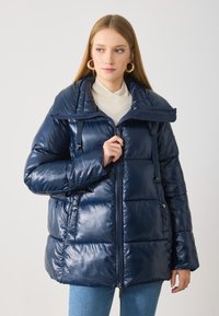 Marineblaue Steppjacke aus glänzendem Material, mit Reißverschluss vorne, großem Kragen und Knopfdetails. Quiltoptik mit lockerem Schnitt.