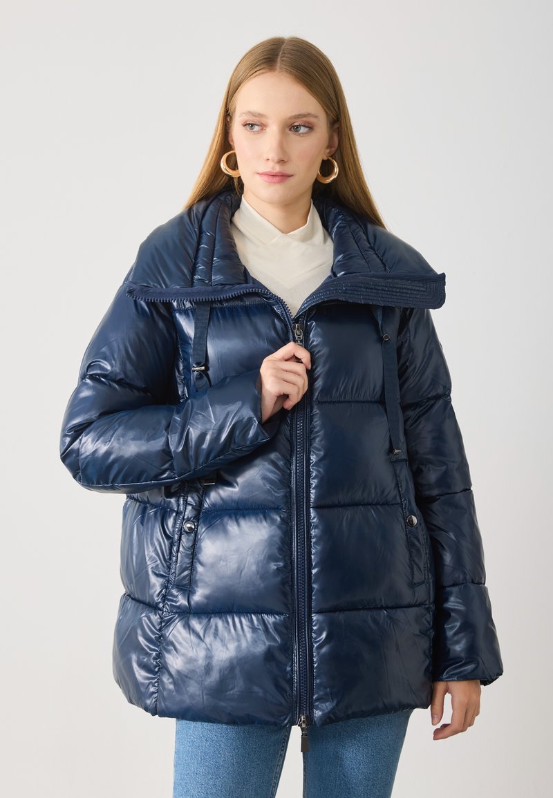 Marineblaue Steppjacke aus glänzendem Material, mit Reißverschluss vorne, großem Kragen und Knopfdetails. Quiltoptik mit lockerem Schnitt.