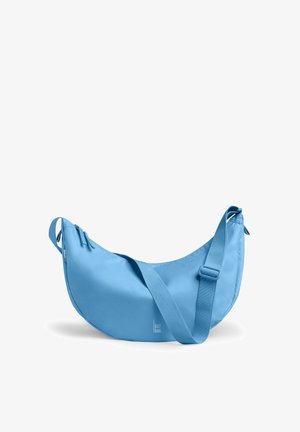 Sac bandoulière bleu clair en forme de croissant avec bandoulière réglable et fermeture éclair, portant la mention "GOT BAG" à l'avant.