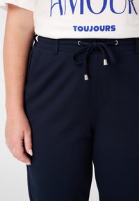 Navyblauwe sweatpants met een gestructureerde afwerking, elastische tailleband en trekkoord. Voorzien van schuine zakken en zilverkleurige hardwareaccenten.