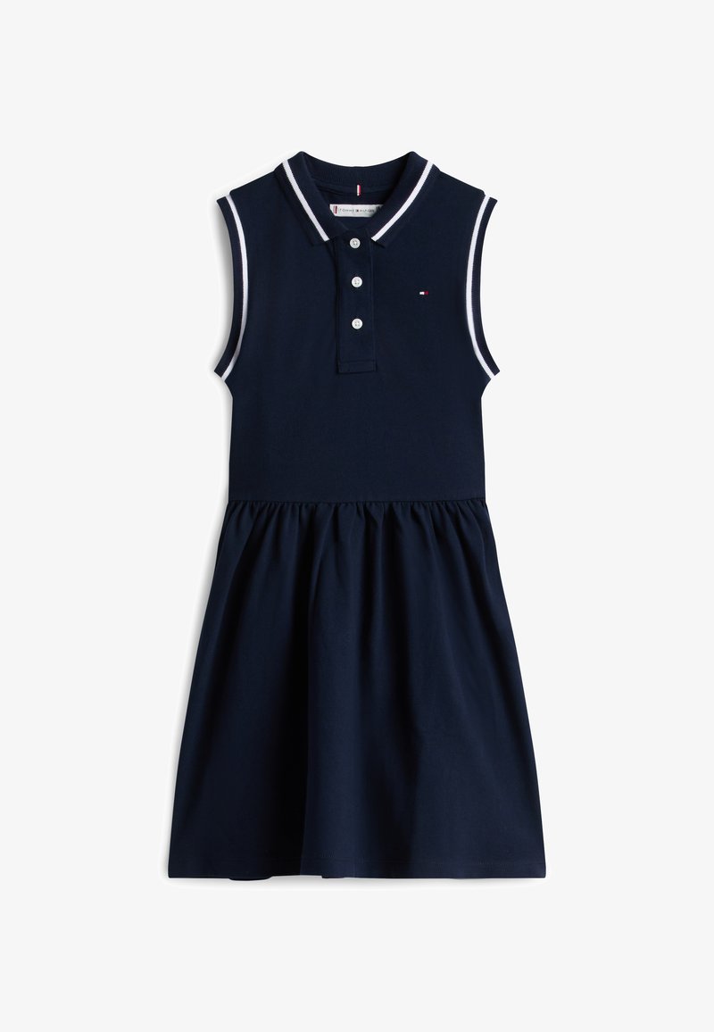 Σκούρο μπλε αμάνικο φόρεμα με γιακά, τρεις κουμπότρυπες, και αντίθετη λευκή λεπτομέρεια στον γιακά και στις μασχάλες· φούστα με πιέτες.