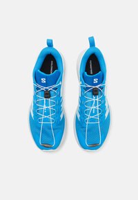 Baskets de sport bleues avec une tige en maille, une semelle blanche, des lacets élastiques et un logo bien visible sur le côté. Conçues pour le confort et la performance.