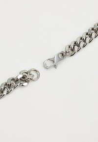 Silver metal chain with oval links and a clasp closure. Smooth, shiny texture with a uniform finish. Curved, interconnected design.
