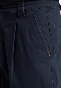 Navyblauwe broek met een gladde textuur, voorzien van een rechte snit, zijzakken en een gouden "Diamond" label op de linkerzak.