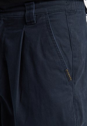 Námořnické modré kalhoty s hladkým povrchem, s rovným střihem, bočními kapsami a zlatou etiketu "Diamond" na levé kapse.