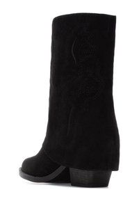 Botín de ante negro hasta el tobillo, con puntera redondeada, tacón de altura media y patrón decorativo de costura en el lado. Textura suave y diseño sencillo.