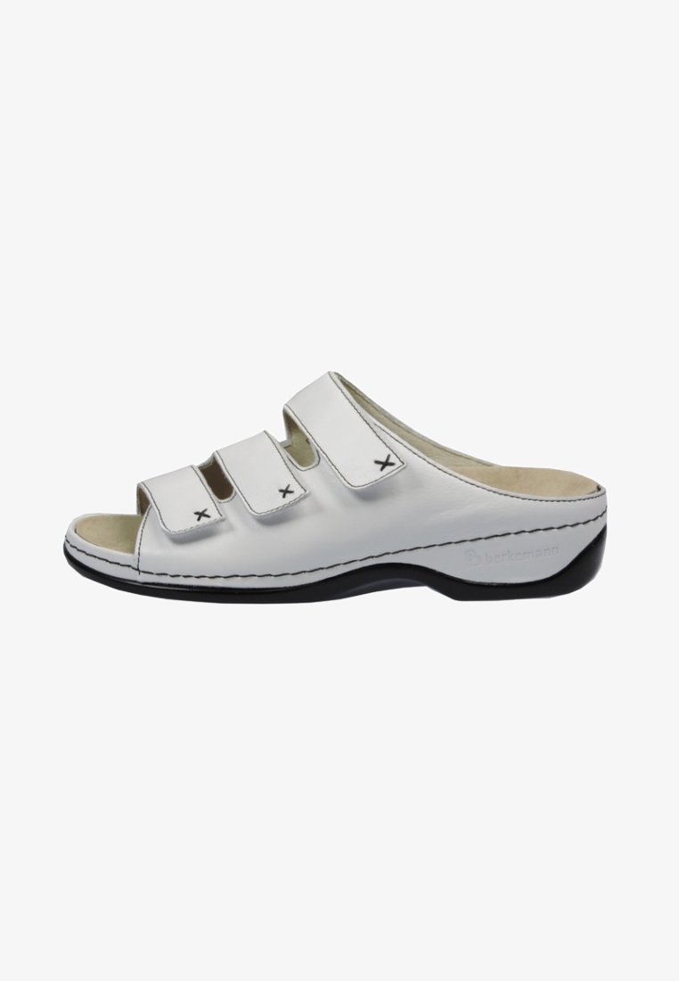 White leather slip-on sandals with three adjustable straps, black accents, and a contoured footbed. Features stitched detailing and open toe.