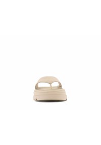 Beige slip-on sandaali, jossa on sileä mokkanahka yläosa, avonainen varvasmuotoilu ja teksturoitu kumipohja pitämään otetta. Yksinkertainen, minimalistinen esteettisyys.