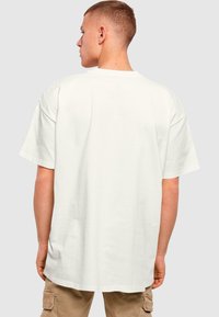 Hvid bomulds t-shirt med en afslappet pasform, sænkede skuldre og korte ærmer, der har en rund halsudskæring og en glat, blød struktur.