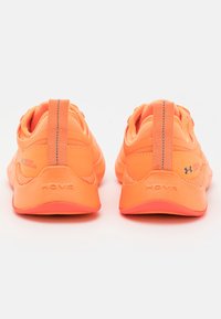 Orangemissiga träningsskor med en texturerad mesh-övre, vadderad krage och slitstark sula med "HOVR"-logotyp på hälen och sidan.