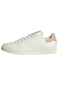 Hvide lærreds sneakers med en struktureret overflade, lysebrun læderhæltap, og seks øjer. Har perforeret detaljer og en gummisål.