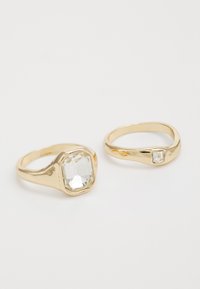 Zwei goldene Ringe: der eine hat einen großen, facettierten rechteckigen Stein; der andere einen kleineren, quadratischen Stein. Beide haben glatte Bänder.